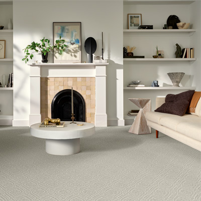 grey patterned carpet in living room with tan couch, stone coffee table, and tiled fireplace.